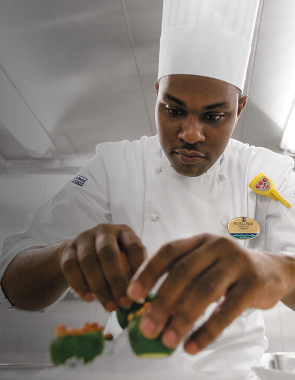 Chef preparing a dish in a cruise restaurant.